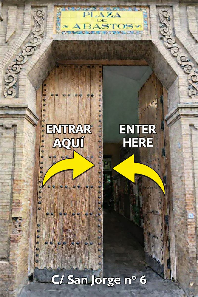Puerta de madera del Mercado de Triana en la Calle San Jorge número 6, con flechas indicando la entrada al teatro