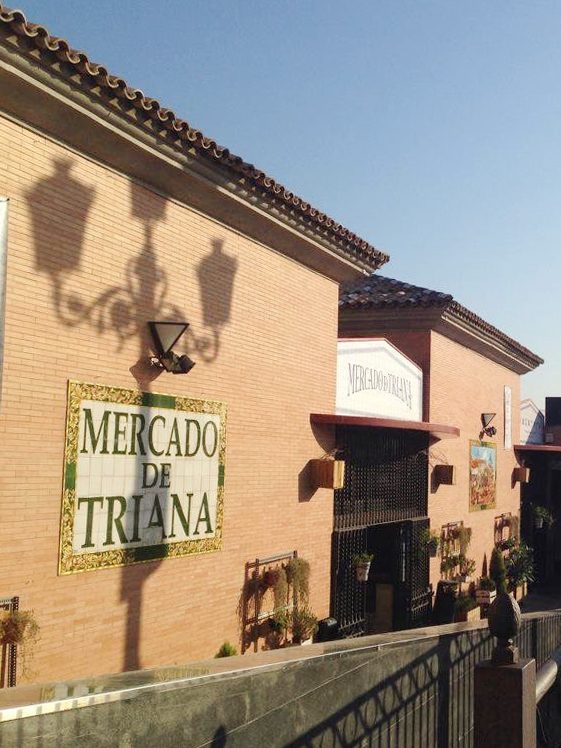 El rótulo de azulejos «Mercado de Triana» en el muro de ladrillo de la fachada, con la entrada al mercado unos metros más allá