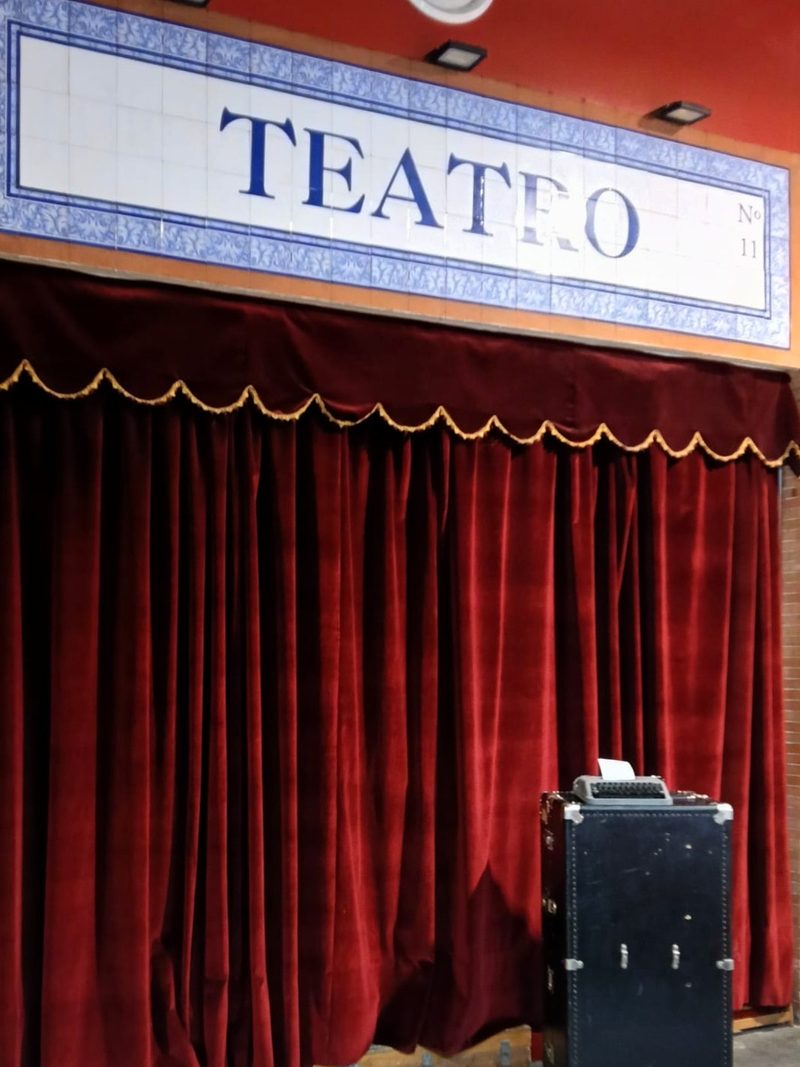 El rótulo de azulejos que dice «Teatro Nº 11», sobre el telón granate de la entrada, con un baúl antiguo y una máquina de escribir al lado